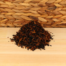 A small pile of pipe tobacco on a wodden base with a wicker background