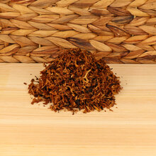 A small pile of pipe tobacco on a wodden base with a wicker background