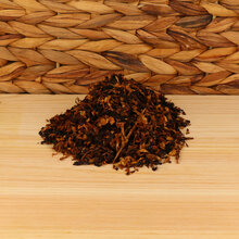 A small pile of pipe tobacco on a wodden base with a wicker background