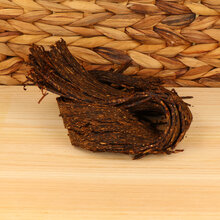 A small pile of flake tobacco on a wodden base with a wicker background
