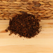 A small pile of pipe tobacco on a wodden base with a wicker background
